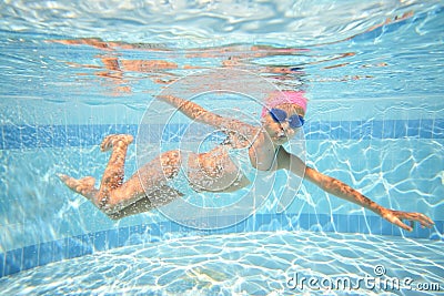Little girl in swimming goggles swimming underwater