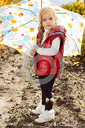 Little girl with umbrella in red vest outdoor