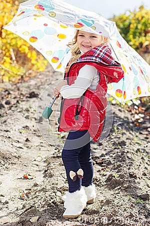 Little girl with umbrella in red vest outdoor