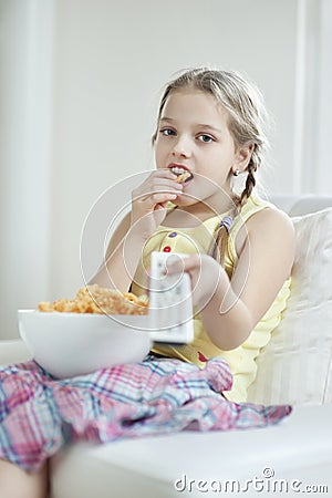 Little girl watching TV as she eats wheel shape snack pellets