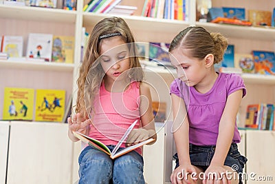 Little girls are concentrated in the library reading a book
