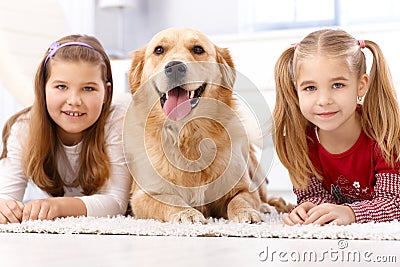 Little girls and dog lying on floor smiling