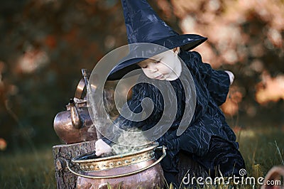 Little halloween witch with couldron outdoors