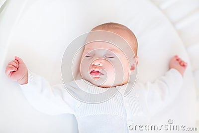 Little newborn baby boy sleeping in white round crib