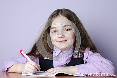 Little school girl doing homeworks at desk