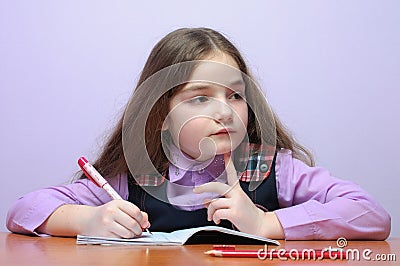 Little school girl doing homeworks at desk