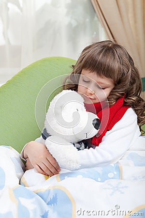 Little sick girl with scarf embraces toy bear