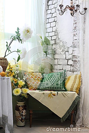 Living room interior corner with colored pillows, vases and flowers