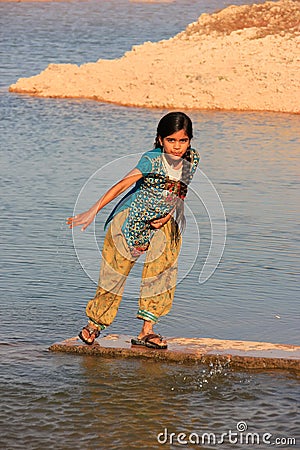 Local girl playing near water reservoir, Khichan village, India