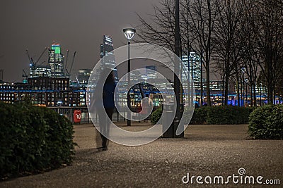 London skyline with an unrecognizable woman walking at night