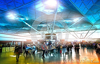 LONDON STANSTED AIRPORT, UK - MARCH 23, 2014: Passengers in the airport departure aria, waiting by the information desk, looking o