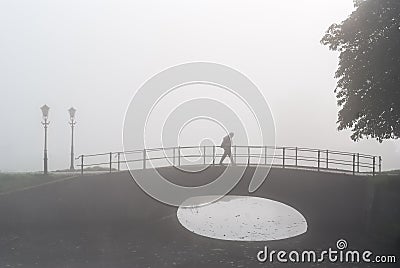 Lone hiker on sad morning walk over a bridge