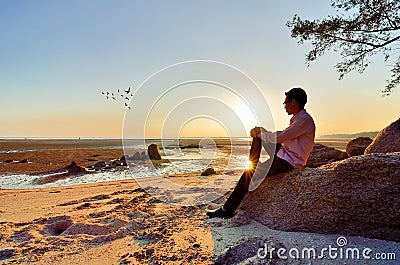 A lonely man sitting on the rock