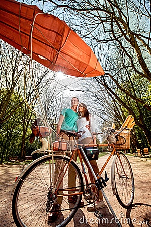 Lovely young couple standing and hugging behind the bicycle with
