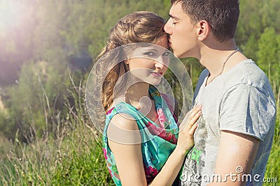Loving beautiful couple of guys and girls in the field walking man kissing the girl s forehead