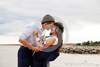Loving bride and groom kissing on the pier.