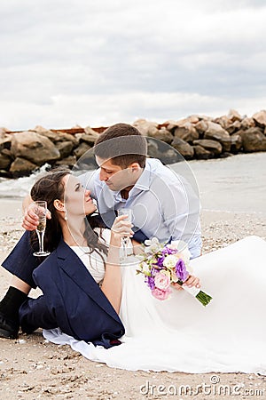 Loving bride and groom sitting on the seashore.
