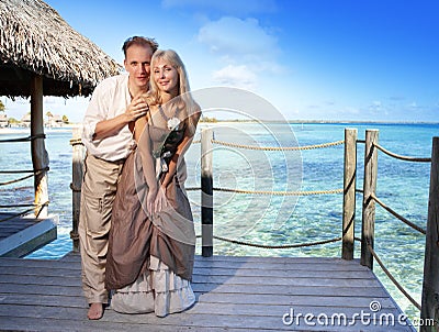 Loving couple on a wooden platform over the sea on the tropical island