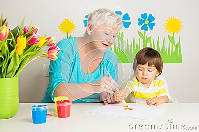 Loving grandma teaching grandson drawing at home