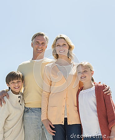 Loving Parents And Children Standing Against Clear Blue Sky