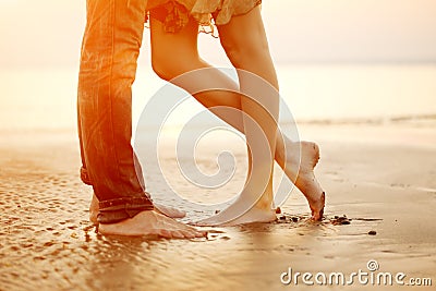 A loving young couple hugging and kissing on the beach at sunset