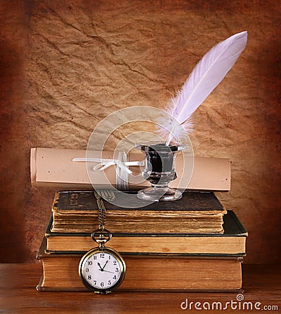 Low key image of white Feather, inkwell and ancient books on old wooden table
