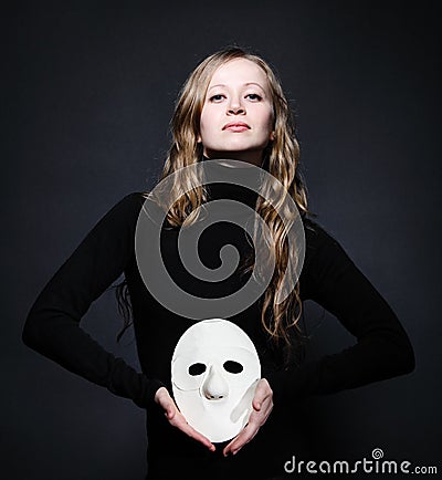 Low key portrait of a beautiful woman holding mask