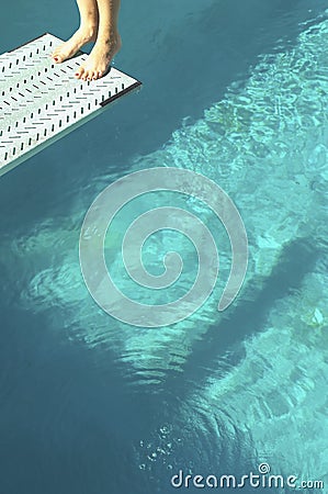 Low Section Of A Diver Standing Backwards On Diving Board Over Pool
