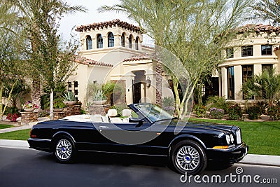 Luxurious convertible car parked in front of a mansion house