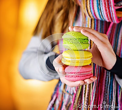 Young woman holding the french pastry macaron in c