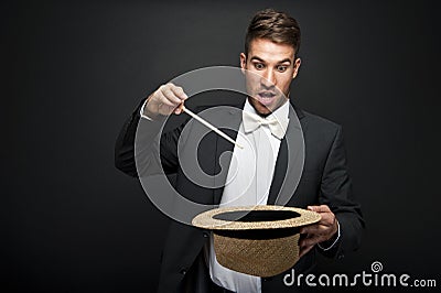 A magician in a black suit holding an empty top hat