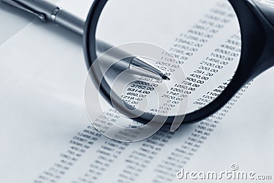 Magnifying glass and pen over financial report