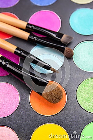 Make-up brushes and colorful eyeshadow palette over black