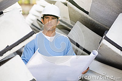 Male architect with blueprint working at construction site