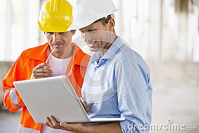 Male architects working on laptop at construction site