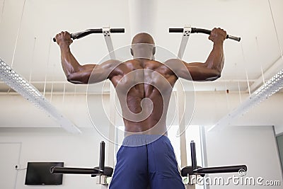 Male body builder doing pull ups at the gym