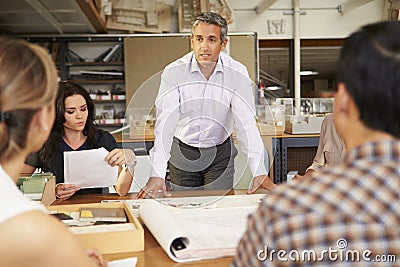 Male Boss Leading Meeting Of Architects Sitting At Table