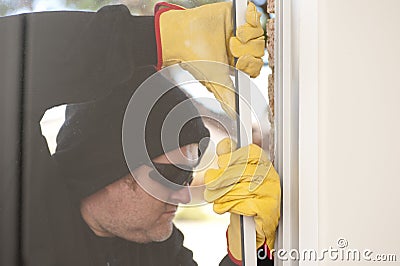 Burglar breaking through window of house