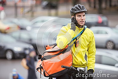 Male Cyclist With Courier Bag Using Mobile Phone