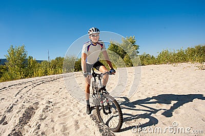 Male cyclist riding a bike stopped rolling on the sand