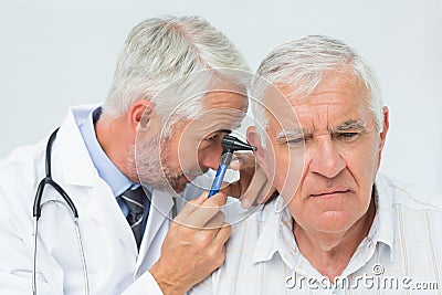 Male doctor examining senior patient s ear