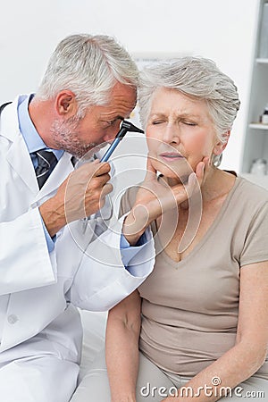 Male doctor examining senior patient s ear