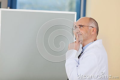 Male Doctor With Finger On Lips Standing By Flipchart