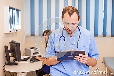 Male doctor using a tablet computer in a hospital. In a backgrou