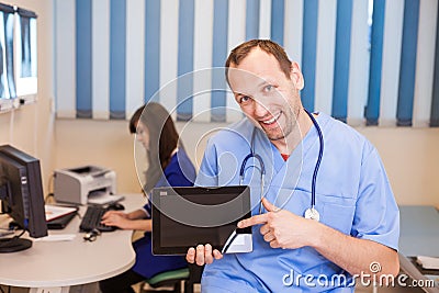 Male doctor using a tablet computer in a hospital. In a backgrou