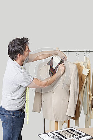 Male dressmaker adjusting suit on tailor s dummy in design studio