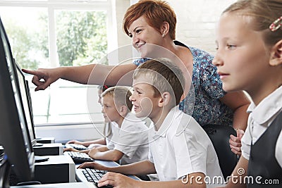 Male Elementary Pupil In Computer Class With Teacher