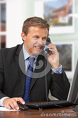 Male Estate Agent Talking On Phone At Desk