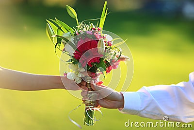 Male and female hands holding bouquet of flowers