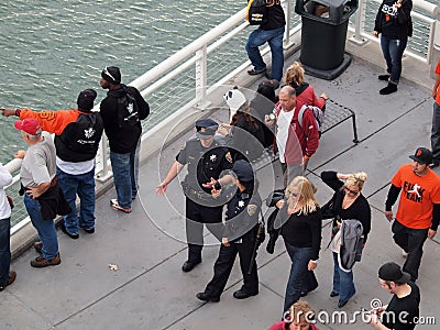 Male and female SFPD police officers walk down promenade along w